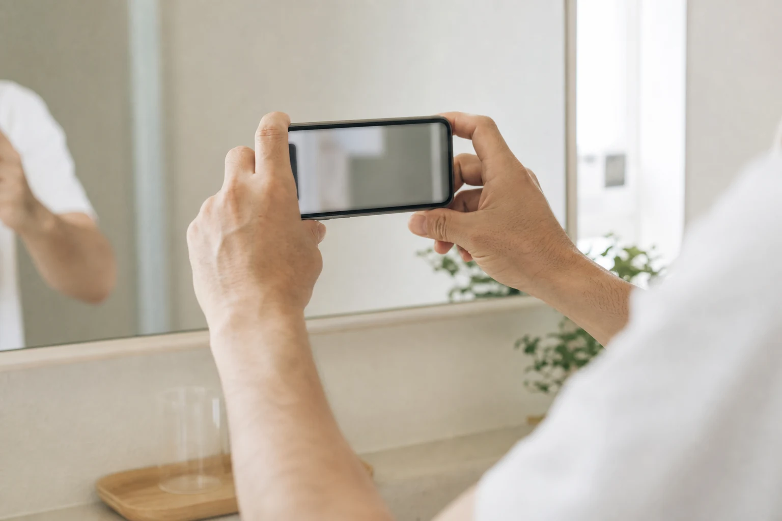 朝の洗面所でスマートフォンを使い記録する手元